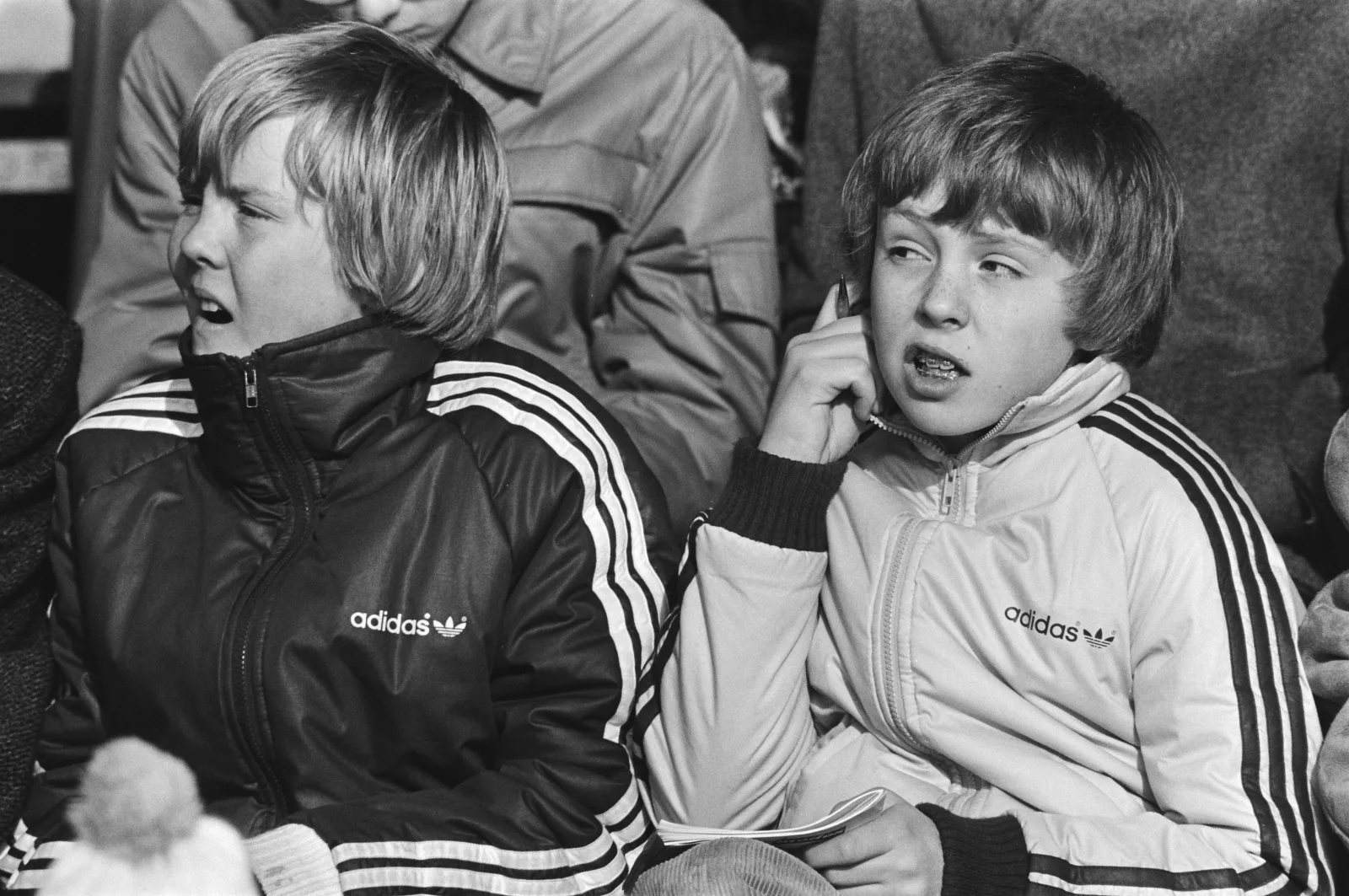 De jonge prinsen Willem-Alexander en Johan Friso in Adidas trainingspakken op de tribune bij het WK Sprintschaatsen in Alkmaar 1982